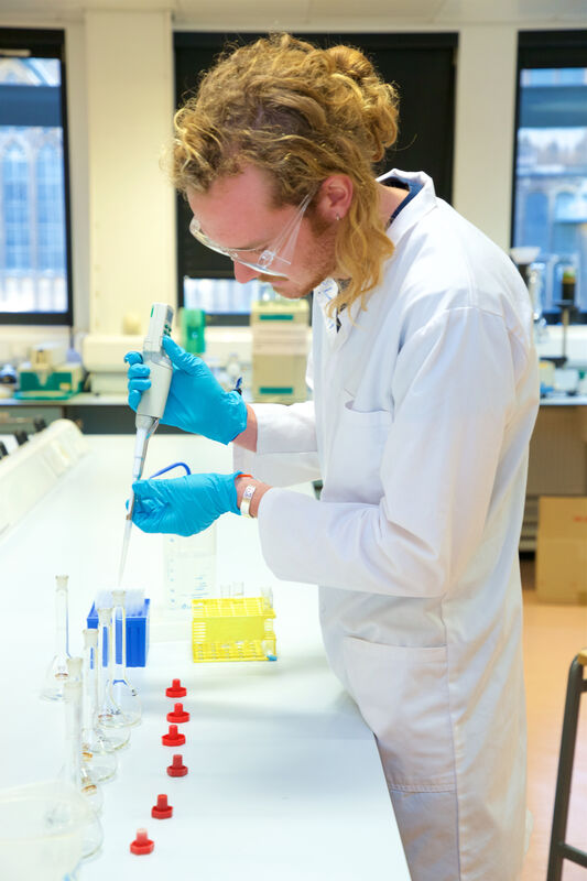 A student in a laboratory testing liquids in test tubes